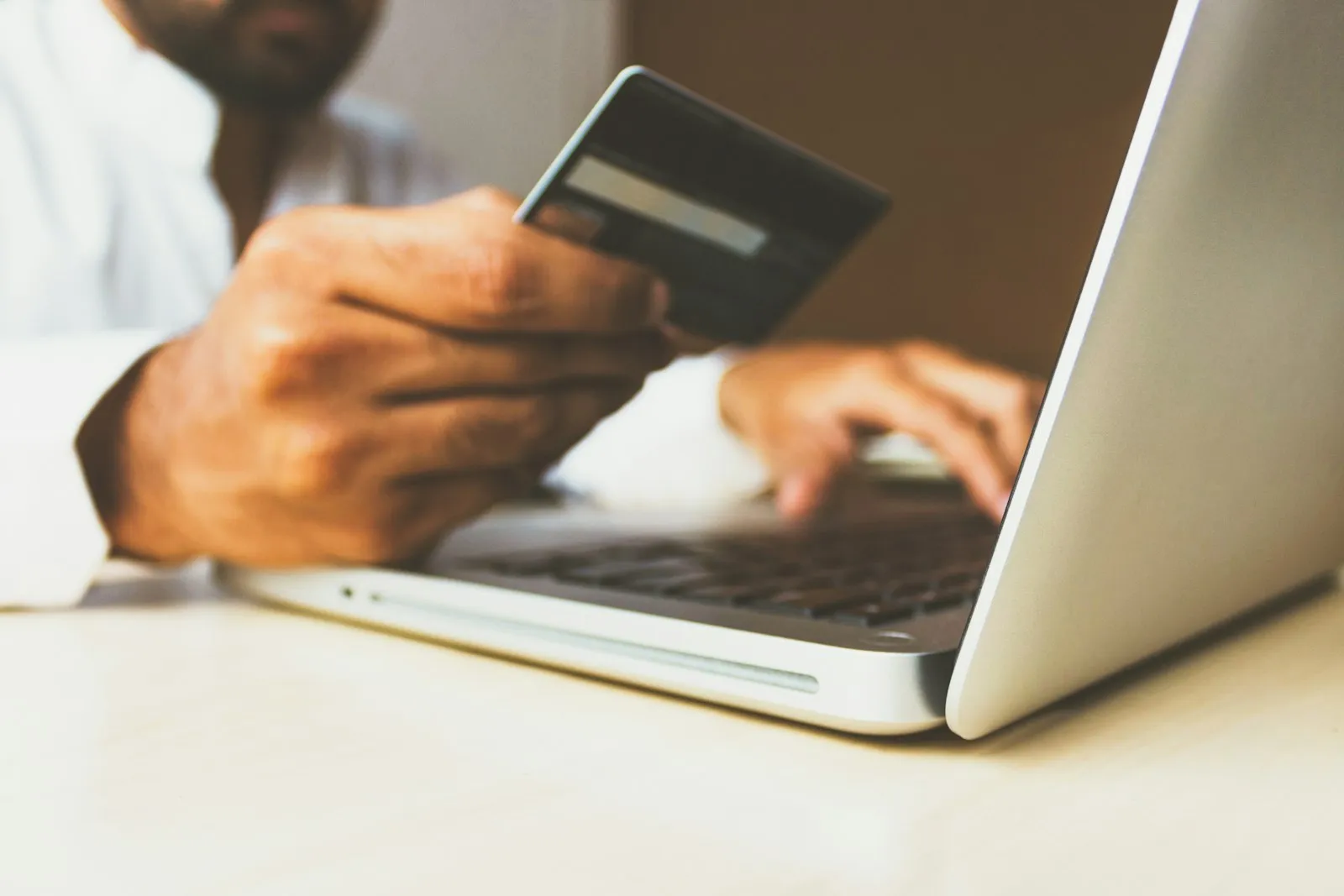 Person using a laptop while holding a payment card