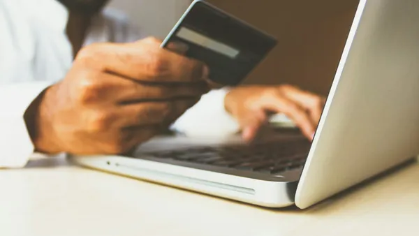 Person using a laptop while holding a payment card