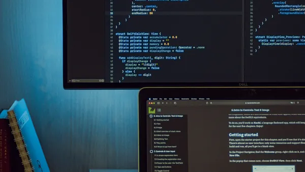 Monitor and laptop displaying code and a programming tutorial