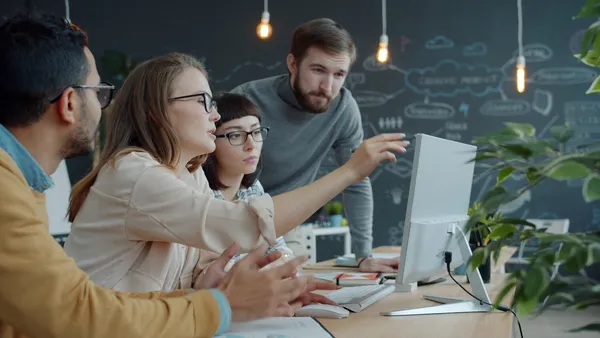 Team collaborating around a laptop in an office