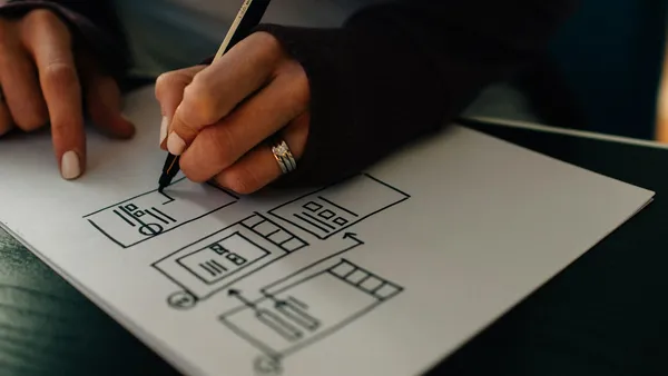 Hands drawing a website wireframe on white paper