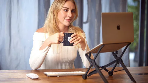 Woman sitting at a table working on a laptop with a cup of coffee