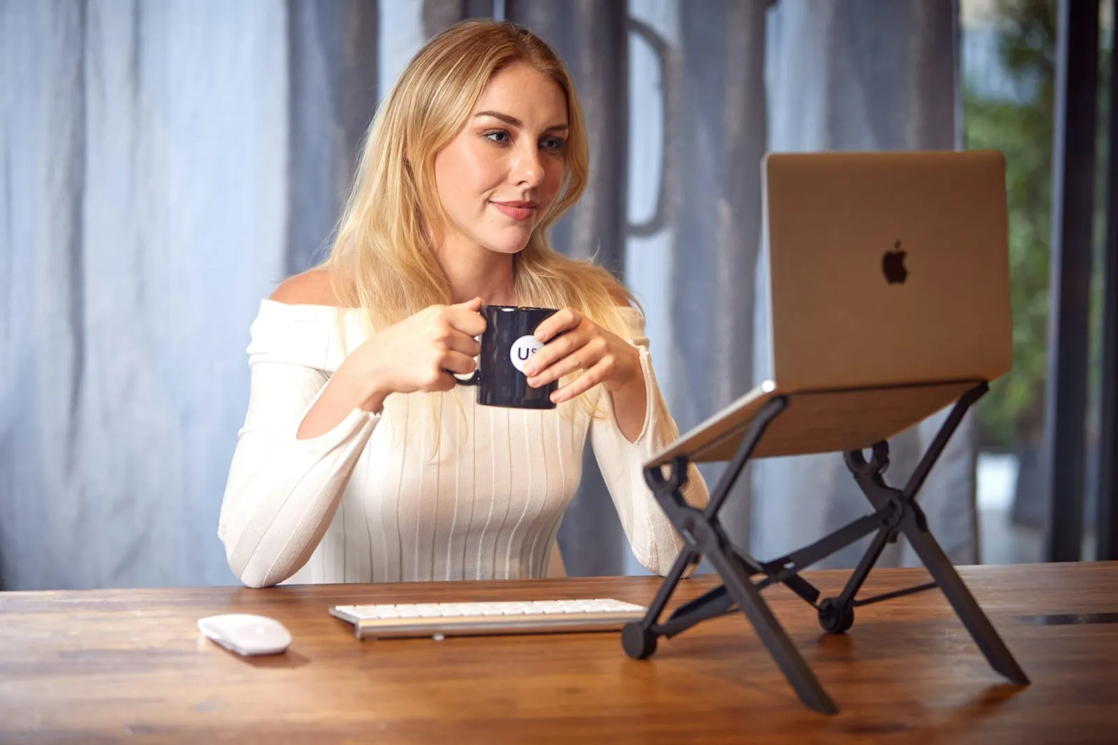 Woman sitting at a table working on a laptop with a cup of coffee