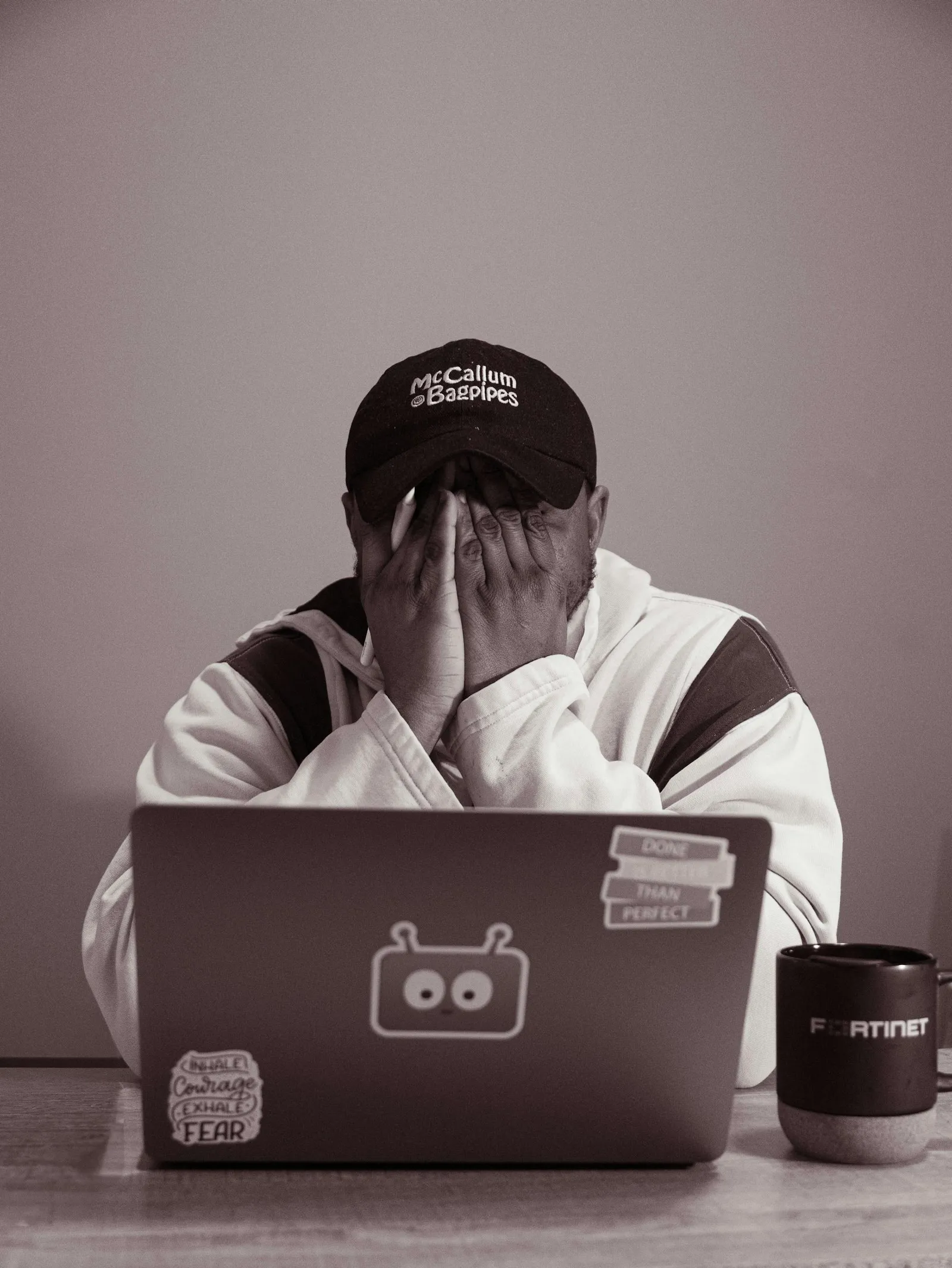 Person sitting at a laptop with hands over their face