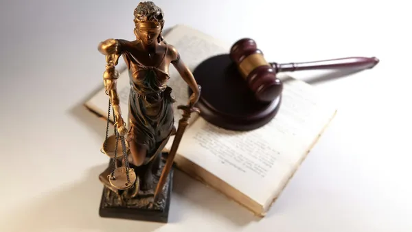 Statue of justice, a gavel, and an open book on a table