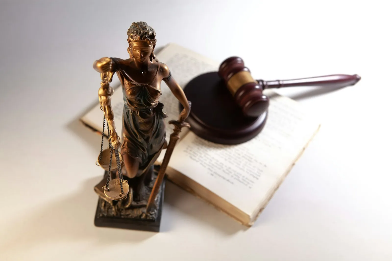 Statue of justice, a gavel, and an open book on a table