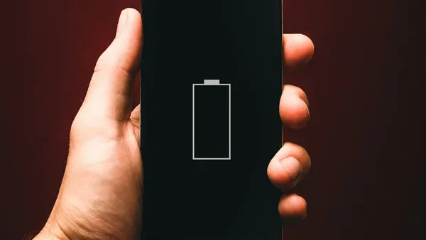 Person holding a smartphone showing a low battery warning